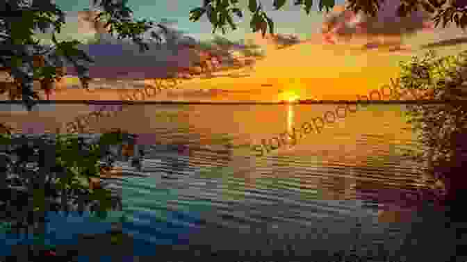 A Breathtaking Sunset Over A Tranquil Lake, Casting A Warm Glow On The Surrounding Landscape In The Fresh Green